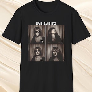 May include: Black t-shirt with a sepia-toned photo collage of a woman wearing sunglasses and a black top. The text "EVE BABITZ" is printed above the photo collage. The shirt is made of a soft, comfortable material.
