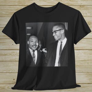 Könnte beinhalten: Schwarzweißfoto von Martin Luther King Jr. und Malcolm X, die nebeneinander stehen. Das Foto ist auf ein schwarzes T-Shirt gedruckt.