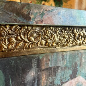 May include: A close-up of a dark green and blue painted wooden frame with a gold ornate border. The frame is textured and has a distressed look.