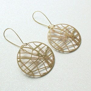 May include: A pair of gold-toned earrings featuring a circular design with a detailed city map pattern.