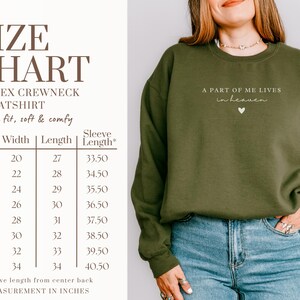Op de afbeelding: Maattabel voor een unisex crewneck sweatshirt in verschillende maten van S tot 5XL. De tabel toont de breedte, lengte en mouwlengte in inches. De tekst "A part of me lives in heaven" is op het sweatshirt gedrukt.