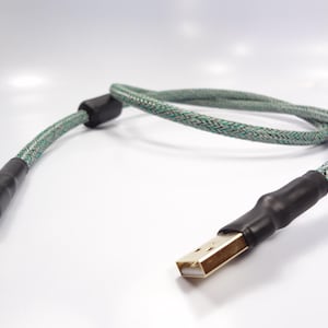 Puede incluir: Un cable USB trenzado verde y negro con conectores chapados en oro.