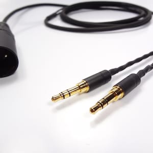 May include: A black audio cable with a 4-pin XLR connector on one end and two 3.5mm stereo jacks on the other end.