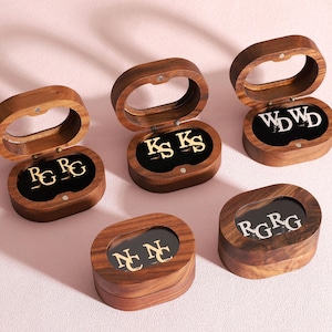 May include: A white ceramic mug with a black handle and the text "But First, Coffee" in a bold, black font. The mug is set against a blurred background, suggesting a cozy setting.