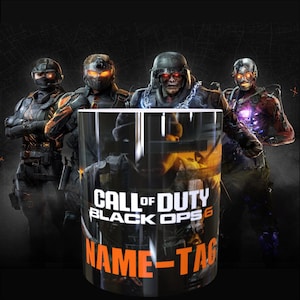 May include: A cylindrical ceramic mug featuring a graphic print of four armoured soldiers in a dark, tactical setting. The mug displays the text "CALL OF DUTY BLACK OPS 6" in white and orange, with the words "NAME-TAG" printed in bold orange letters below.