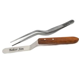 May include: Stainless steel offset spatula with a wooden handle and a pair of stainless steel tweezers. Both tools are engraved with the text "Baker Jim". The spatula is angled for easy frosting and the tweezers are designed for precision.