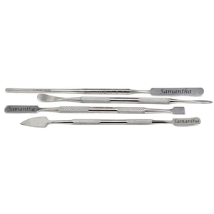 May include: A set of four stainless steel tools with textured handles and various shaped ends. Each tool has the name "Samantha" engraved on it. The tools are arranged horizontally against a white background.