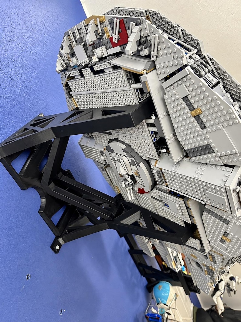 Pu&ograve; includere: Un grande e dettagliato modello di astronave realizzato con mattoncini di plastica grigi, montato su un supporto da parete nero angolare. Il modello presenta complesse texture meccaniche, torrette circolari e accenti rossi.