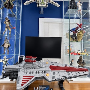 K&ouml;nnte beinhalten: Ein gro&szlig;es LEGO Star Wars Venator-class Star Destroyer Modell in Grau und Dunkelrot, auf einem schwarzen St&auml;nder mit zwei kleinen Minifiguren und einer Plakette. Das Schiff zeigt detaillierte Rumpfplatten, Triebwerke und rote Streifen.