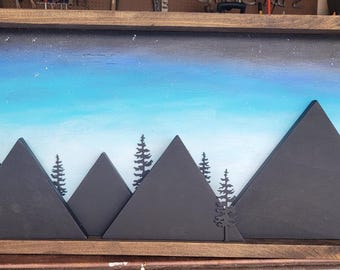 May include: A framed painting of a mountain range with a blue and white sky. The mountains are black and the sky is painted with a starry night effect. The painting is in a wooden frame.