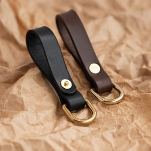 May include: Two leather keyrings with brass rings. One keyring is black and the other is brown.