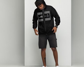 May include: A black zip-up hoodie with a gray and white graphic design featuring the text "Sh" and a geometric pattern. The model is wearing black shorts and white sneakers.
