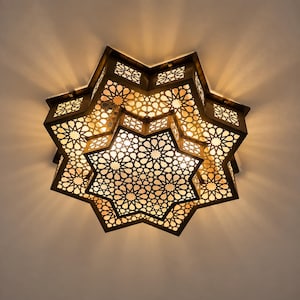 May include: A star-shaped flush mount ceiling light fixture with a dark metal frame featuring intricate geometric cutouts. The design consists of layered, multi-pointed star shapes that cast warm, patterned light shadows onto the ceiling surface.