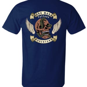 May include: Navy blue t-shirt with a detailed graphic of a skull, snake, wings, and the text "DARK MARK TATTOOS KNOCKTURN". The design is in brown, green, and white.