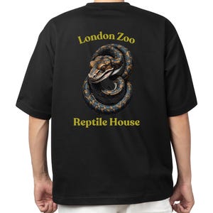Op de afbeelding: Zwart T-shirt met een afbeelding van een slang en de tekst "London Zoo Reptile House" gedrukt op de achterkant.