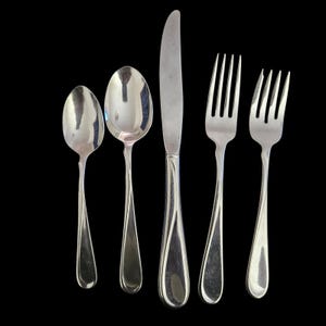 May include: A five-piece stainless steel flatware set consisting of two spoons, one dinner knife, and two forks. Each piece features a polished silver finish and a smooth, tapered handle design with a subtle curved line detail.