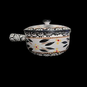 May include: A ceramic lidded pot with a handle, featuring a cream-colored base decorated with black leaf motifs and small yellow and red floral accents. The rim and handle are adorned with a black and white speckled pattern on a cream background.
