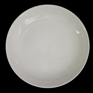 May include: A white, round ceramic plate with a slightly curved rim. The plate has a glossy finish and is set against a black background. This simple, elegant dish is suitable for serving various meals.