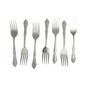 May include: A set of seven silver-toned metal forks arranged in a row. Each fork features a four-tined head and a handle decorated with an embossed floral pattern. The forks vary slightly in length and design, showcasing a metallic finish.