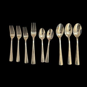 May include: A set of nine stainless steel flatware pieces arranged in a row against a black background. The collection includes four forks of varying sizes and five spoons, all featuring a polished, reflective silver finish and tapered handles.