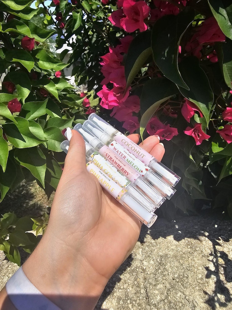 May include: Five clear lip gloss tubes with colorful labels. The labels feature fruit designs and names like "Coconut", "Water Melon", "Strawberry", "Pineapple", and "Mango".