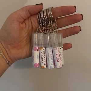 May include: A set of small, clear spray bottles on a silver keyring. Each bottle features a label with text and graphics, including "Pink", "Chocolate Orange", "Cloud", "Bubble Gum", and "Mint Pepper".