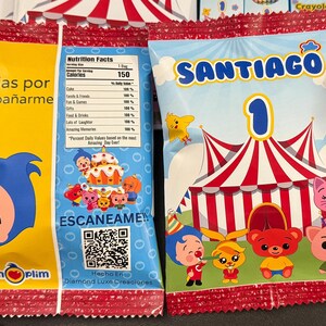 Peut inclure: Sacs de f&ecirc;te color&eacute;s avec des personnages de dessins anim&eacute;s et des motifs de chapiteau de cirque. Un sac dit "Santiago 1" et l'autre "Gracias por acompa&ntilde;arme". Les sacs ont une bordure ray&eacute;e rouge et blanche et contiennent des informations nutritionnelles.