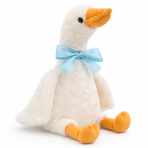 May include: A plush white goose with a light blue bow around its neck. The goose has an orange beak and feet. The stuffed animal is sitting down and has a soft, fluffy texture.