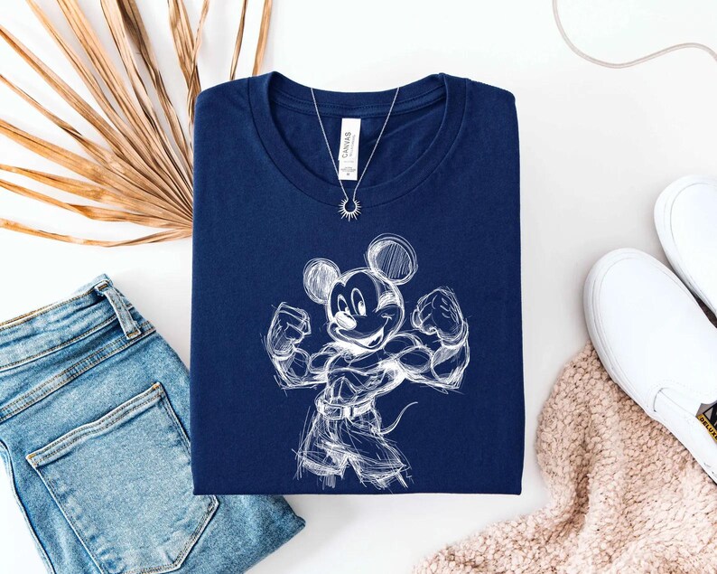 May include: A navy blue short-sleeved t-shirt featuring a white line-art sketch of a muscular cartoon mouse character flexing its arms. The shirt has a crew neckline and a white brand label at the inner collar, displayed with a silver sun pendant.
