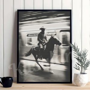 May include: Black and white framed print depicting a cowboy on horseback riding past a subway train. The image is a high-contrast photograph with motion blur, creating a dynamic and artistic effect. The word "SUBWAY" is visible on the train.