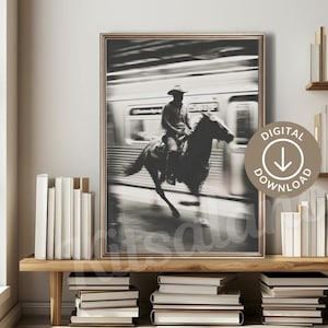 May include: Black and white framed print of a cowboy riding a horse in front of a speeding train. The image is a digital download. The cowboy is wearing a hat and the horse is galloping.