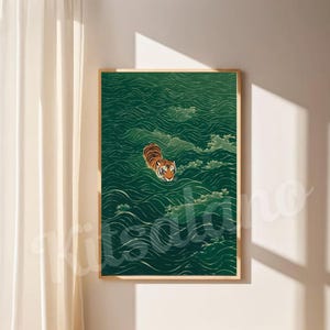 Op de afbeelding: Een rechthoekige wandkunstprint in een lichthouten lijst met een illustratie van een oranje en zwarte tijger die zwemt in diepgroen, golvend water. De tijger is in het midden geplaatst, met de kop boven het wateroppervlak.
