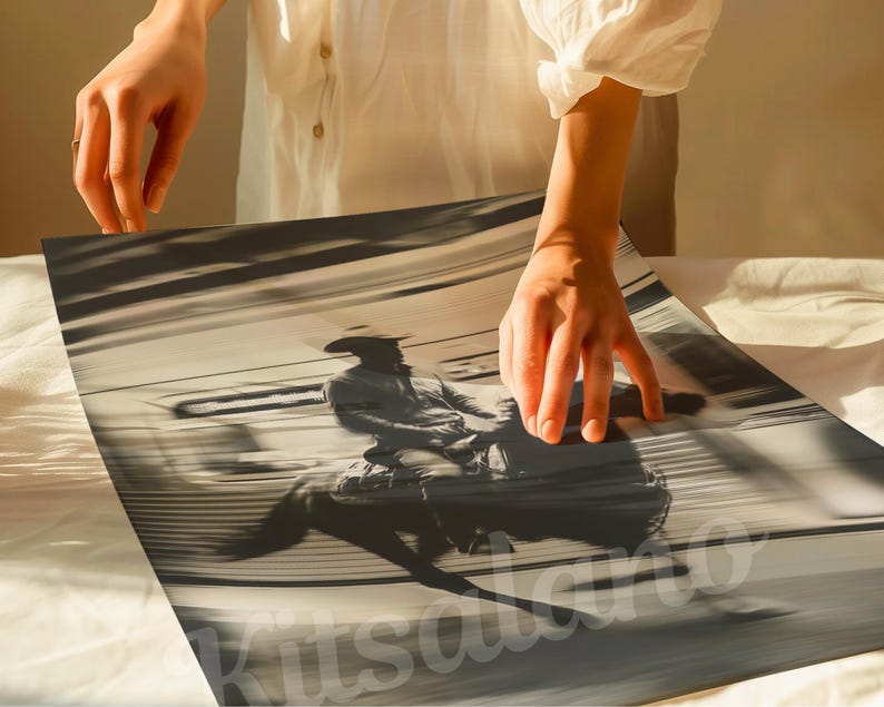 May include: Monochrome print of a cowboy riding a bucking bronco. The image is in shades of gray and sepia, with motion blur suggesting speed. The cowboy is wearing a hat and riding gear. The print is being held by a person.