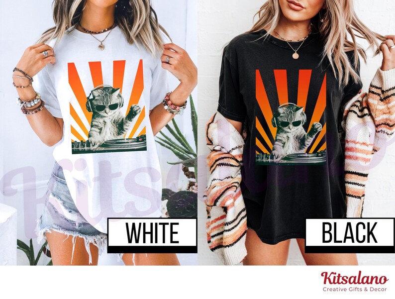May include: White and black t-shirts featuring a graphic of a cat wearing sunglasses and headphones, DJing with a turntable. The cat graphic is set against a backdrop of orange and yellow rays. The word "WHITE" and "BLACK" are displayed on the shirts.