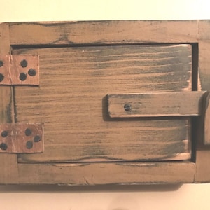 May include: A rustic wooden box with a hinged lid and a latch. The box is made of light brown wood with darker brown accents and copper-coloured metal hinges. The box has a distressed, aged appearance.