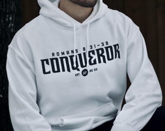 Könnte beinhalten: Weißer Kapuzenpullover mit schwarzem Text, der "Römer 8:31-39 CONQUEROR EST. RO 33" lautet.