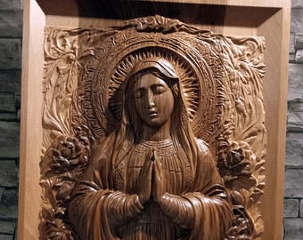 May include: A wooden carving of the Virgin Mary with a halo, surrounded by roses. The carving is in a wooden frame and measures 37 x 30 cm.