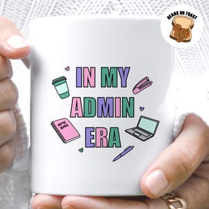 Può includere: Tazza in ceramica bianca con il testo "In My Admin Era" in lettere rosa, verde e viola. La tazza presenta varie illustrazioni a tema ufficio, tra cui una tazza di caffè, una graffatrice, un quaderno, un laptop e una penna.