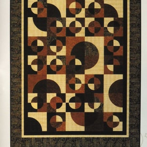 May include: A quilting pattern titled "Lunar Eclipse" by Upper Canada Quiltworks, designed by Christine Baker and Nellie Holmes. The pattern features a geometric design with circles and half-circles in shades of brown, black, and cream.