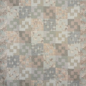 May include: A quilt with a patchwork design featuring various shades of beige, brown, and gray. The quilt is made up of squares of different sizes and patterns, creating a visually interesting and textured surface.