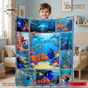 May include: A rectangular fleece blanket featuring a collage of Finding Nemo characters including Nemo, Dory, and Bruce the shark. The center panel displays the text Finding Daniel surrounded by colorful coral reef imagery and various underwater scenes.