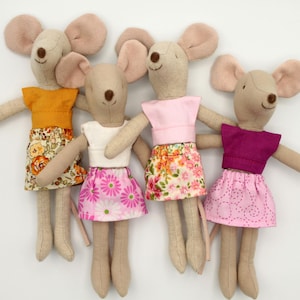 Può includere: Quattro giocattoli di peluche a forma di topo che indossano abiti diversi. I topi sono tutti beige con orecchie e nasi rosa. Indossano gonne e top di vari colori e motivi, tra cui fiori, pois e colori solidi.