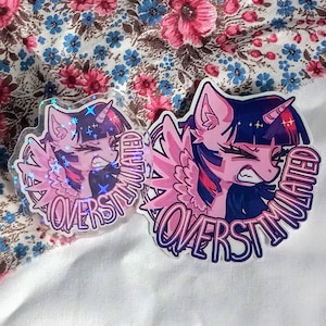Peut inclure: Deux autocollants représentant un poney de dessin animé rose et violet avec une corne de licorne et des ailes. Les autocollants portent l'inscription "OVERSTIMULATED" dans un cercle autour de la tête du poney. Un autocollant a un effet holographique.