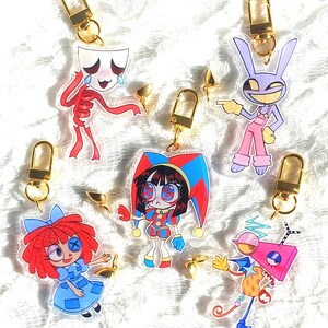 May include: A collection of cartoon character keychains. The keychains feature various designs, including a skeleton, a jester, a rabbit, and a doll. Each keychain has a gold-colored clasp.