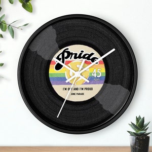May include: A black vinyl record clock with a rainbow pride flag design. The clock face features the text "Pride 45 rpm I'm Out and I'm Proud June Parade".