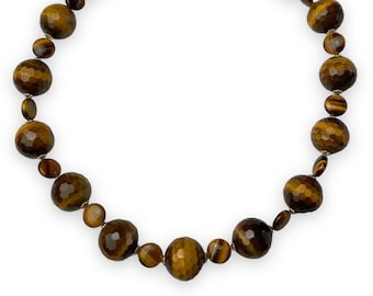 May include: A gold necklace with a clasp closure features faceted tiger's eye beads in shades of brown and gold.