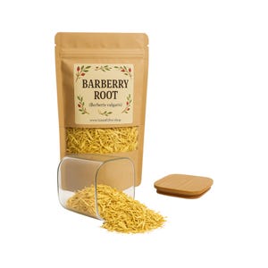 May include: A brown paper bag with a label that reads "Barberry Root (Berberis vulgaris)" and a website address. The bag is filled with yellow dried barberry root pieces. The root is also in a clear glass jar with a wooden lid.