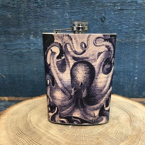 May include: A stainless steel hip flask with a silver cap and a black and white illustration of an octopus on the front.