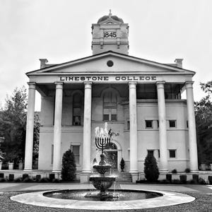 May include: Black and white image of Limestone College. The building features a classical design with columns and a pediment. A fountain is in front of the building. The year 1845 is visible on the tower.