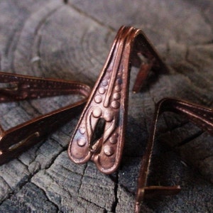 May include: Three antique copper corner protectors with a decorative design. The corner protectors are in the shape of a triangle with a rounded top.